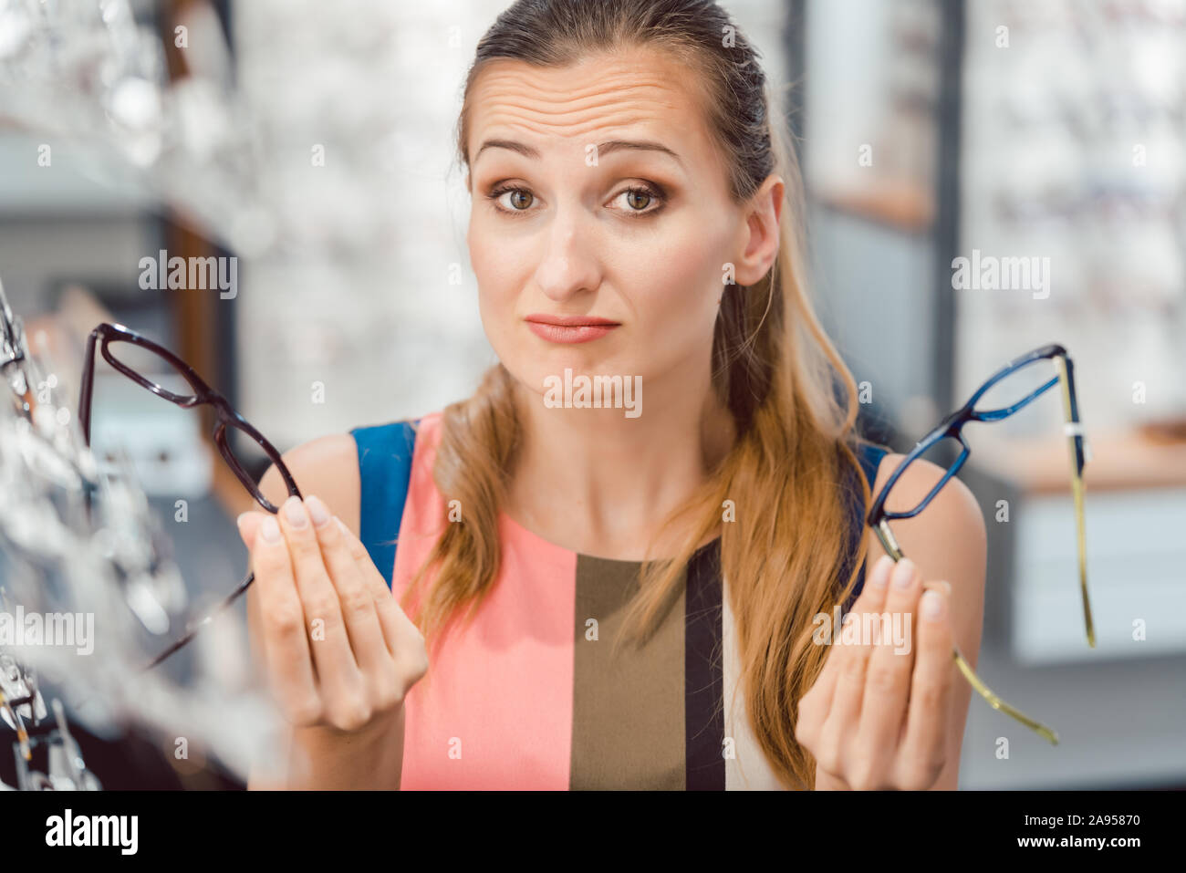 Donna scegliere tra due modelli di occhiali in corrispondenza all'ottico optometrista Foto Stock