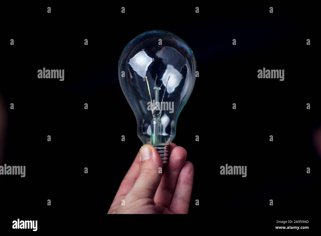 Lampadina della luce in mano davanti a sfondo nero. Energia o idea concept Foto Stock