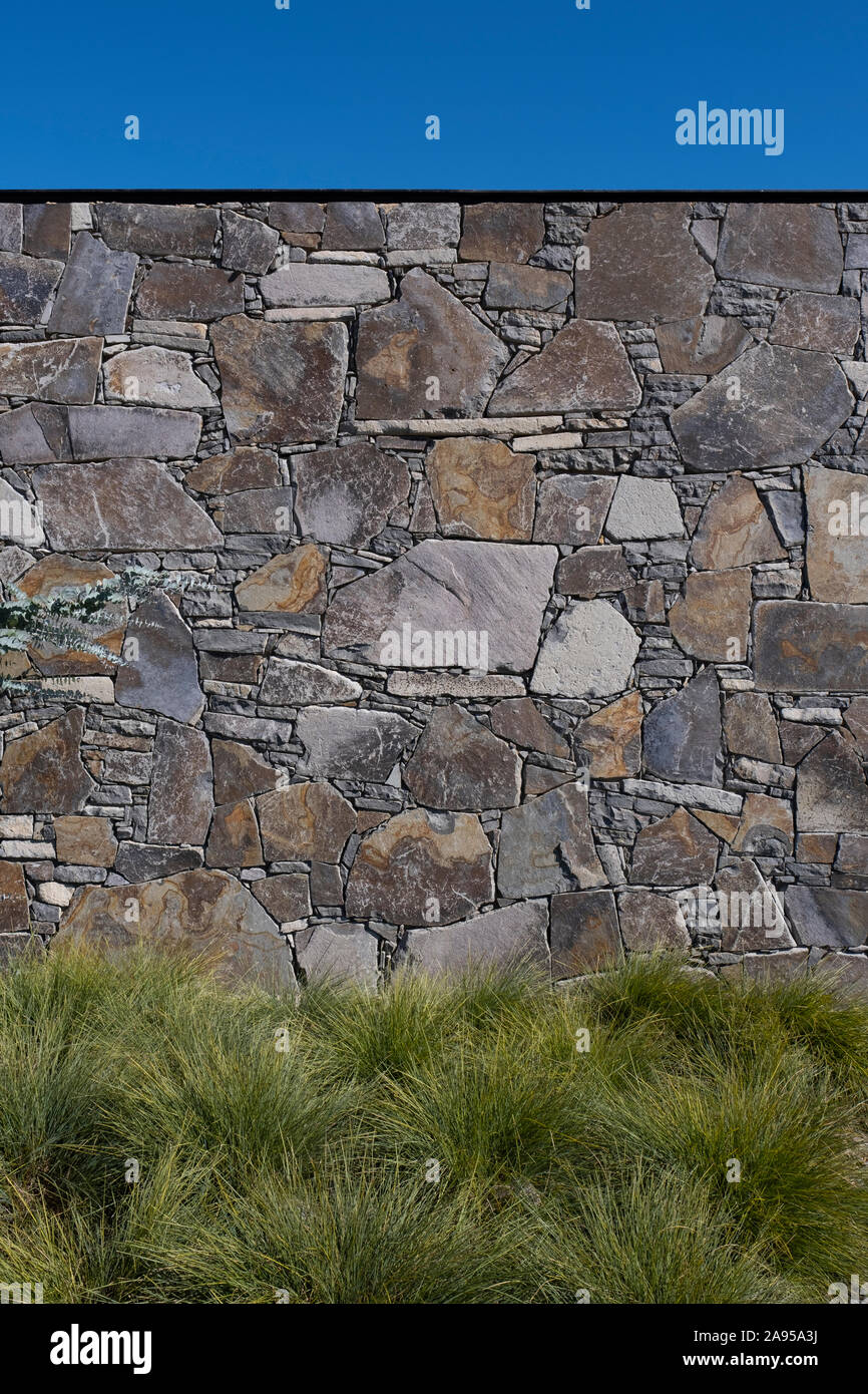 La piantagione di massa di erbe in un paesaggio contro un muro di pietra in una giornata di sole Foto Stock
