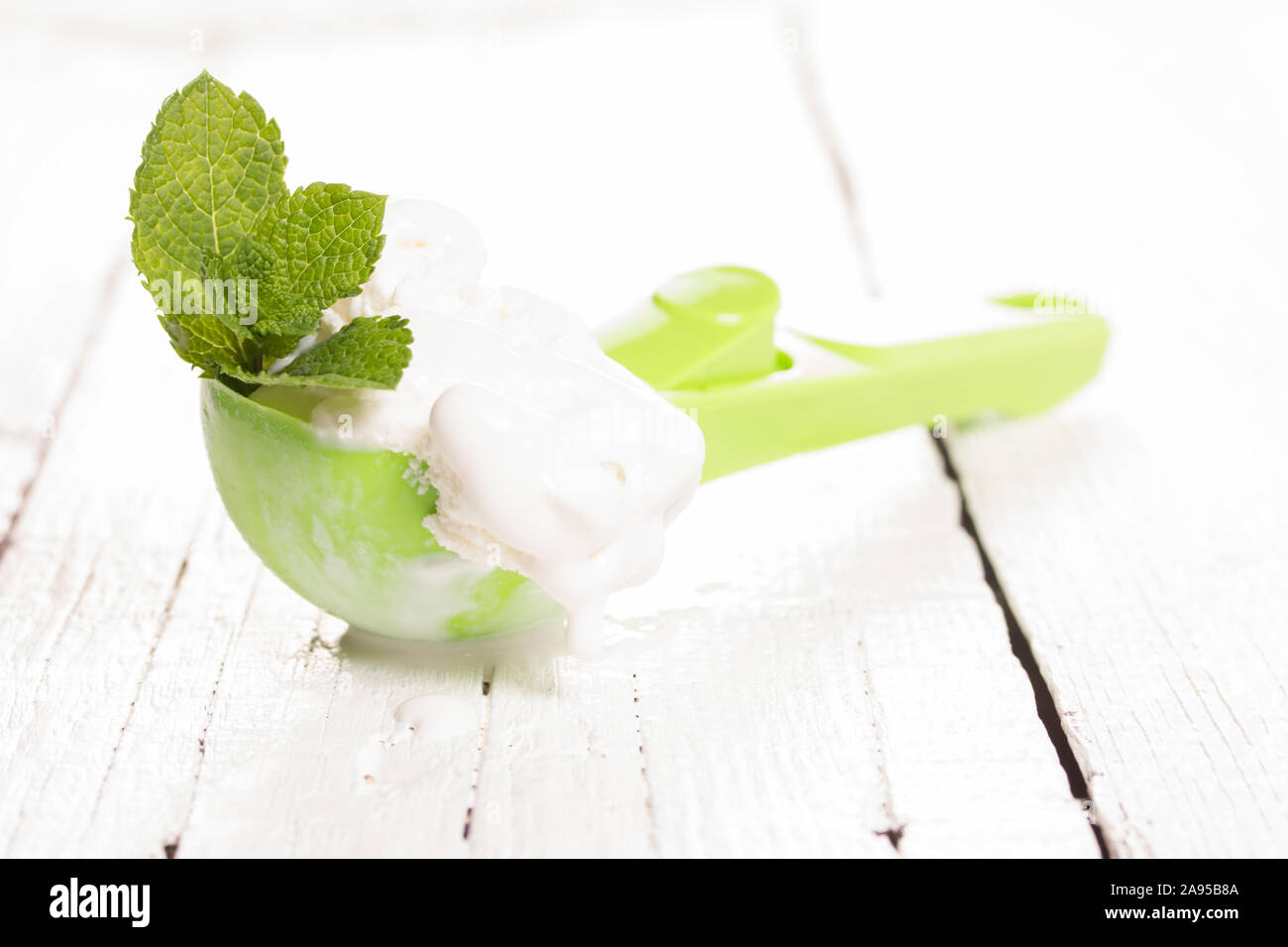 Cucchiaio verde con gelato alla vaniglia e menta Foto Stock