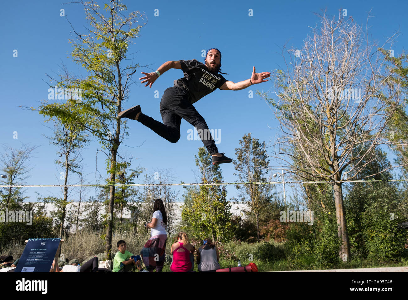 Giovane uomo saltando su una slackline al Wanderlust festival, a Lisbona, Portogallo. Foto Stock