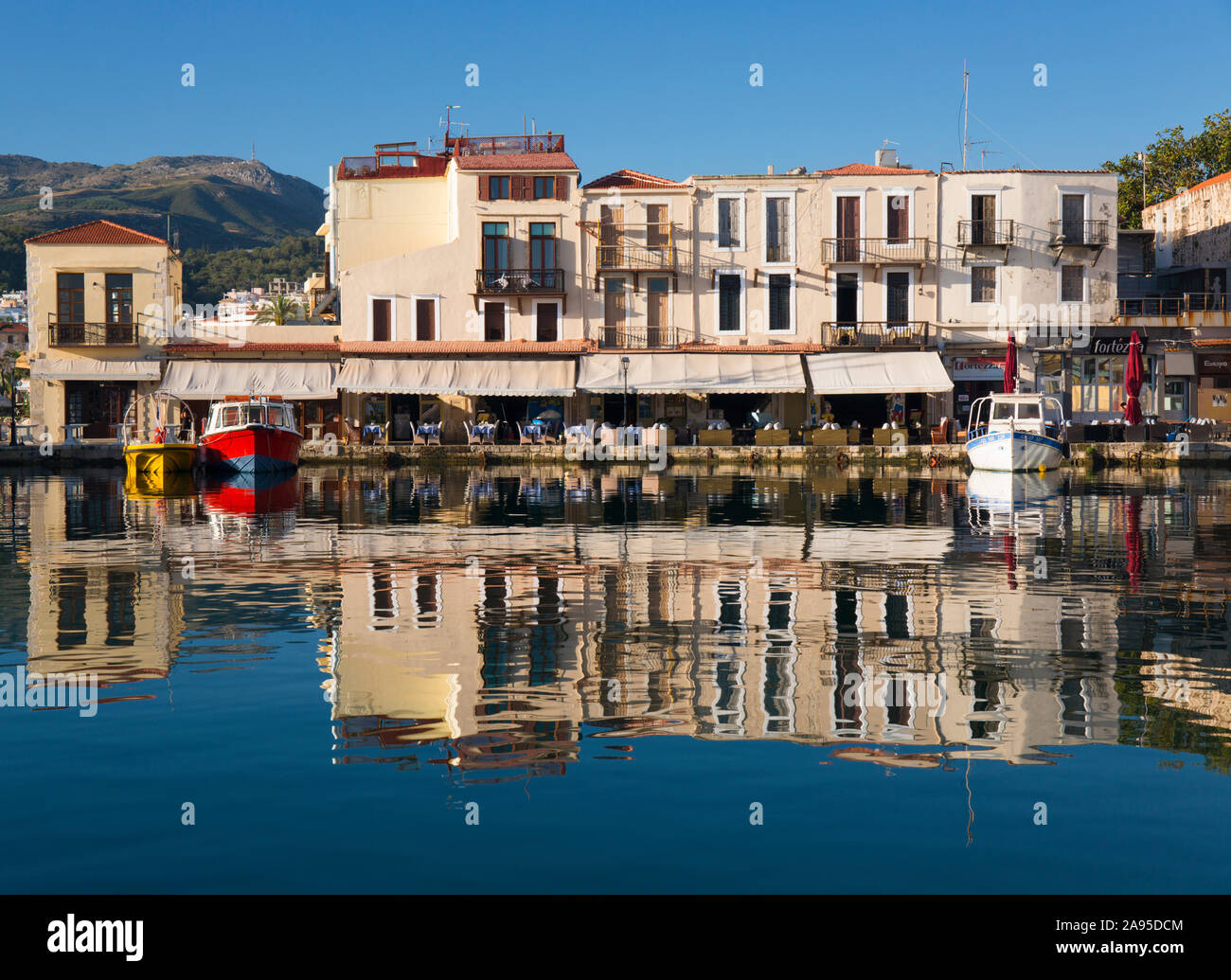 Rethymno, Creta, Grecia. Vista sul porto veneziano, la mattina presto, gli edifici si riflettono in acqua still. Foto Stock