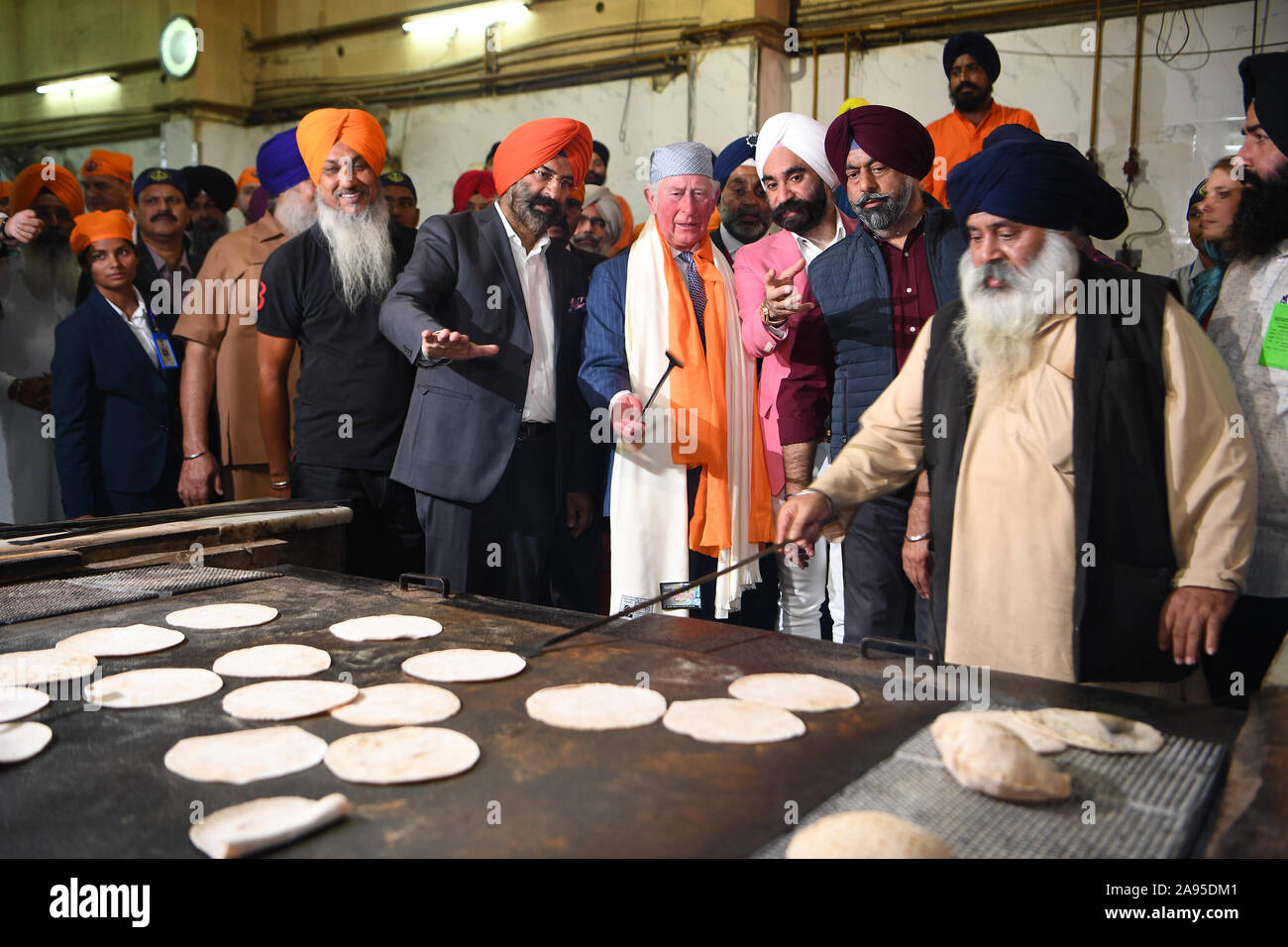 Il Principe di Galles fa un chapati al Bangla Sahib Gurdwara tempio sikh, New Delhi, per celebrare il 550° anniversario della nascita del Guru Nanak, il fondatore della religione sikh, il giorno uno del royal visita in India. Foto Stock