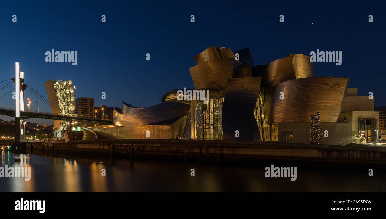 Bilbao cityscape, vista di notte attraverso il fiume Nervion verso l'illuminato il Museo Guggenheim e il Puente de la Salve, Bilbao, Spagna Foto Stock