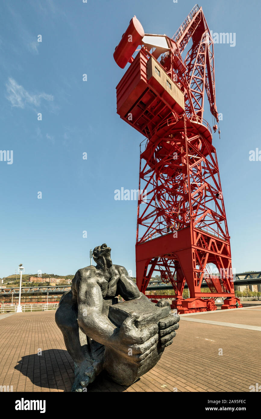 Hombre Tuercebarras (bar la piegatura l'uomo) scultura davanti al rosso ripristinato La Grúa Carola (Carola gru), Bilbao, Spagna Foto Stock