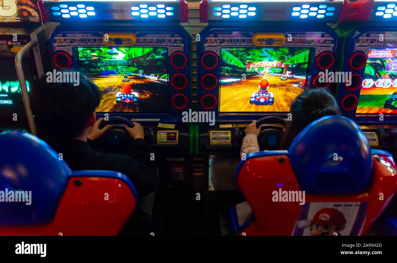 Gli adolescenti giocare un car racing game, Mario Kart, arcade Anata no magazzino, cyberpunk, Kawasaki, Giappone Foto Stock