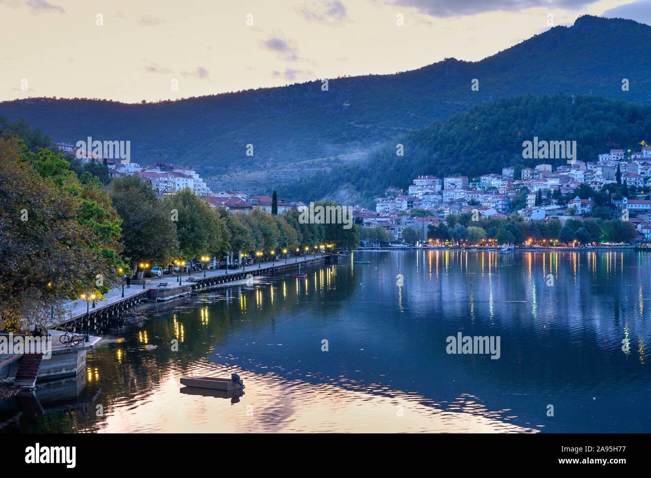 Luce della Sera Sul lungomare nord in Kastoria, guardando attraverso il lago Orestiada con la città sullo sfondo, Macedonia, Grecia settentrionale. Foto Stock