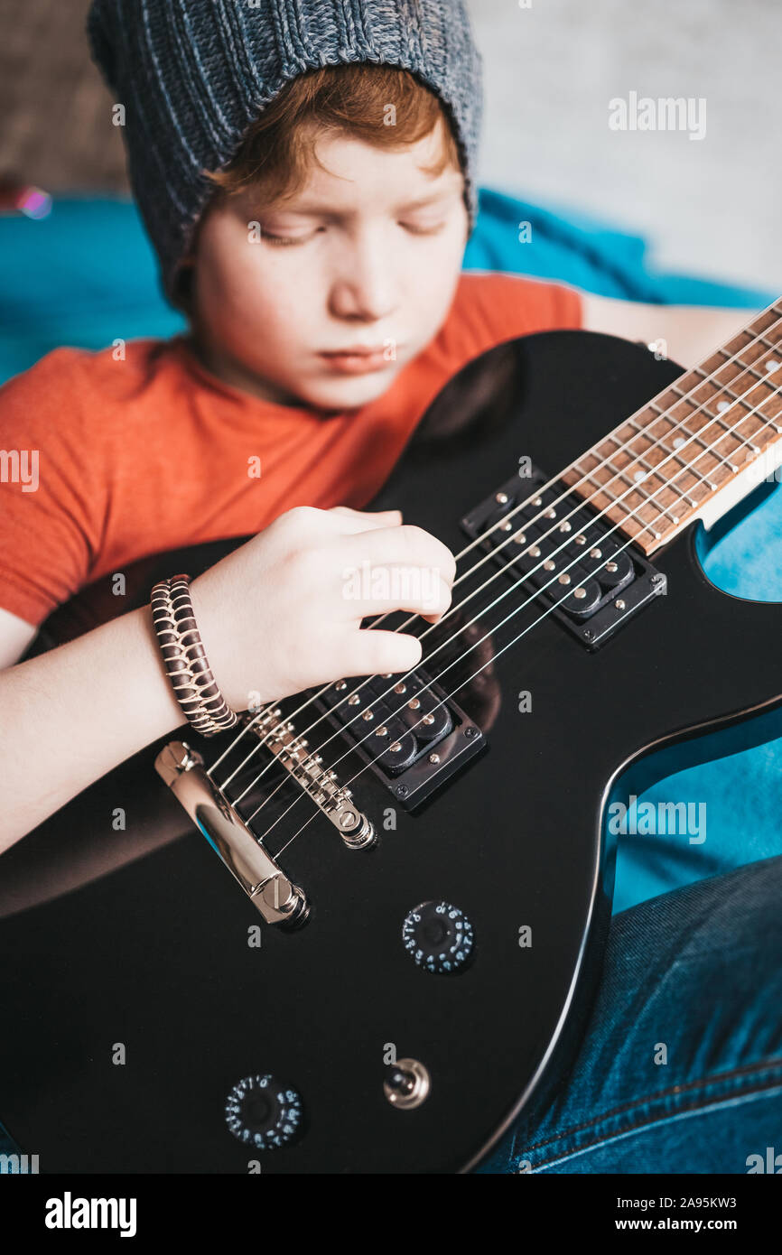 Primo piano di una i capelli rossi elegante ragazzo giocando blues rock su un nero chitarra elettrica Foto Stock