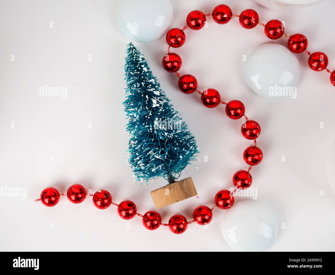 Un piccolo giocattolo albero di Natale sullo sfondo delle palle trasparenti, scheda minimalista per il nuovo anno e di Natale. Foto Stock