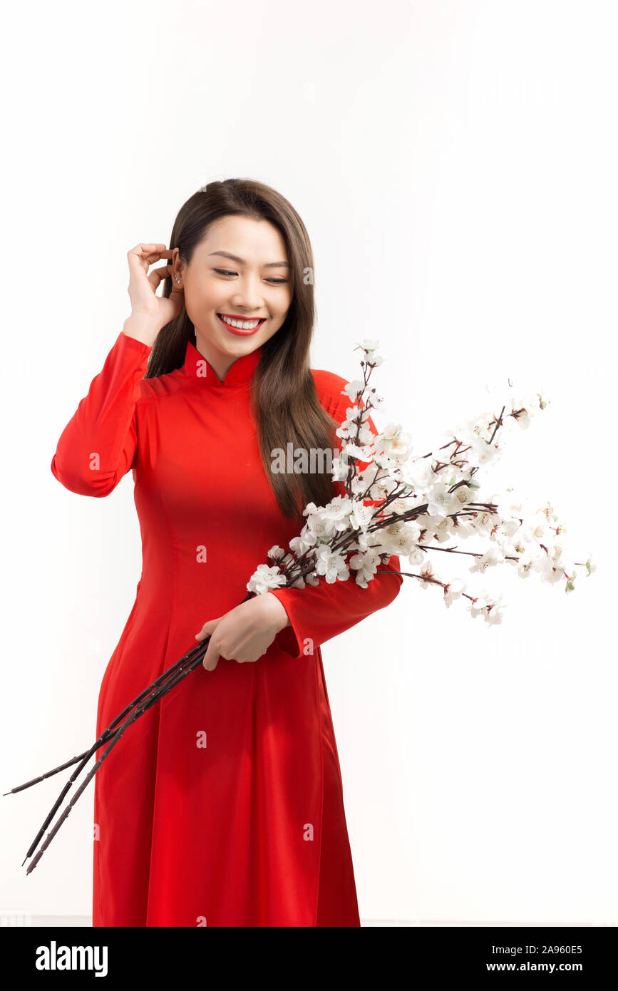 Bella vietnamita donna giovane azienda rami di pesco in fiore Foto Stock