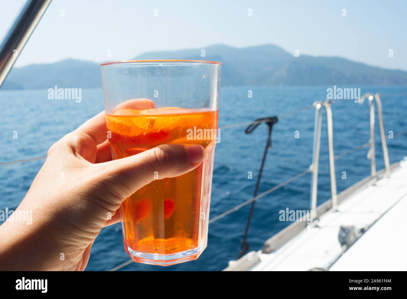 Bicchiere di aperol spritz in mano di una giovane donna, una gita in barca su uno yacht, un partito con bevande analcoliche. Foto Stock