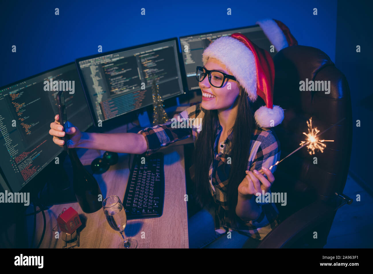 Foto di lavoro coder lady notte di lavoro soddisfare newyear office tenere premuto Telefono sparkler tenendo selfies bere il vino parla di skype usura parenti babbo natale Foto Stock