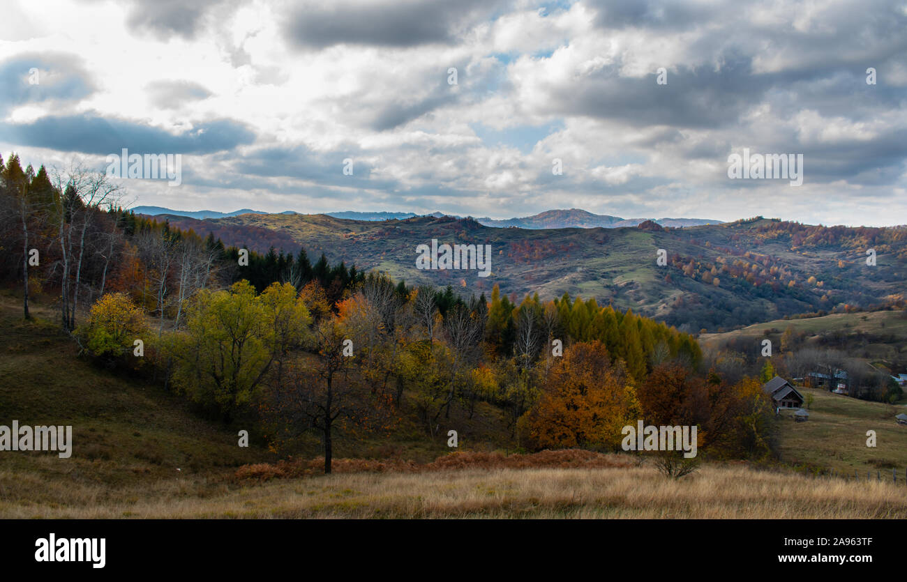 Bellissimo Cielo e nubi su una foresta sulla sommità di una collina nei pressi di un piccolo villaggio, con autunno alberi colorati e i colori autunnali Foto Stock