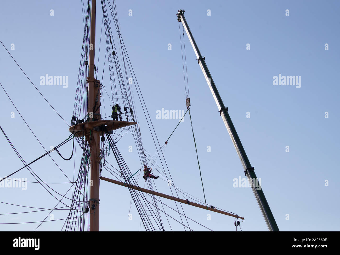 Riggers preparare la randa randa prima di abbassare il mediante la gru dalla mizzenmast sulla Corazzata Vittoriano HMS Warrior, ormeggiata a Portsmouth Historic Dockyard, le navi a montanti e parte del suo bompresso devono essere rimossi per restauro essenziale a Portsmouth. Foto Stock