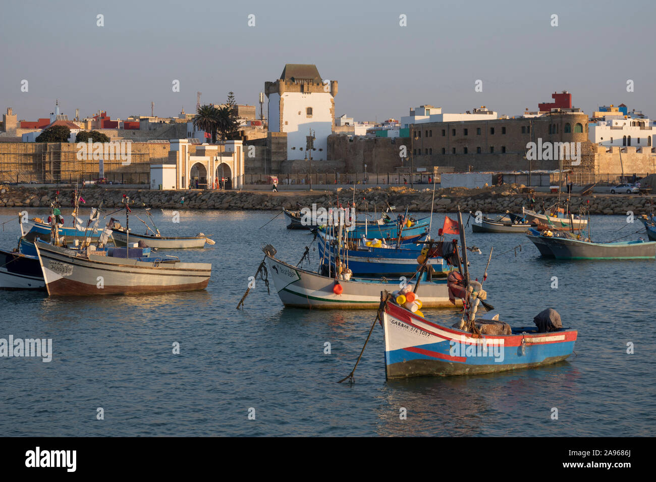 Asilah, Morocco-September 10, 2019: tradizionale blu barche da pesca nel porto di Asilah con torre Al-Kamra nella medina sullo sfondo , Moro Foto Stock