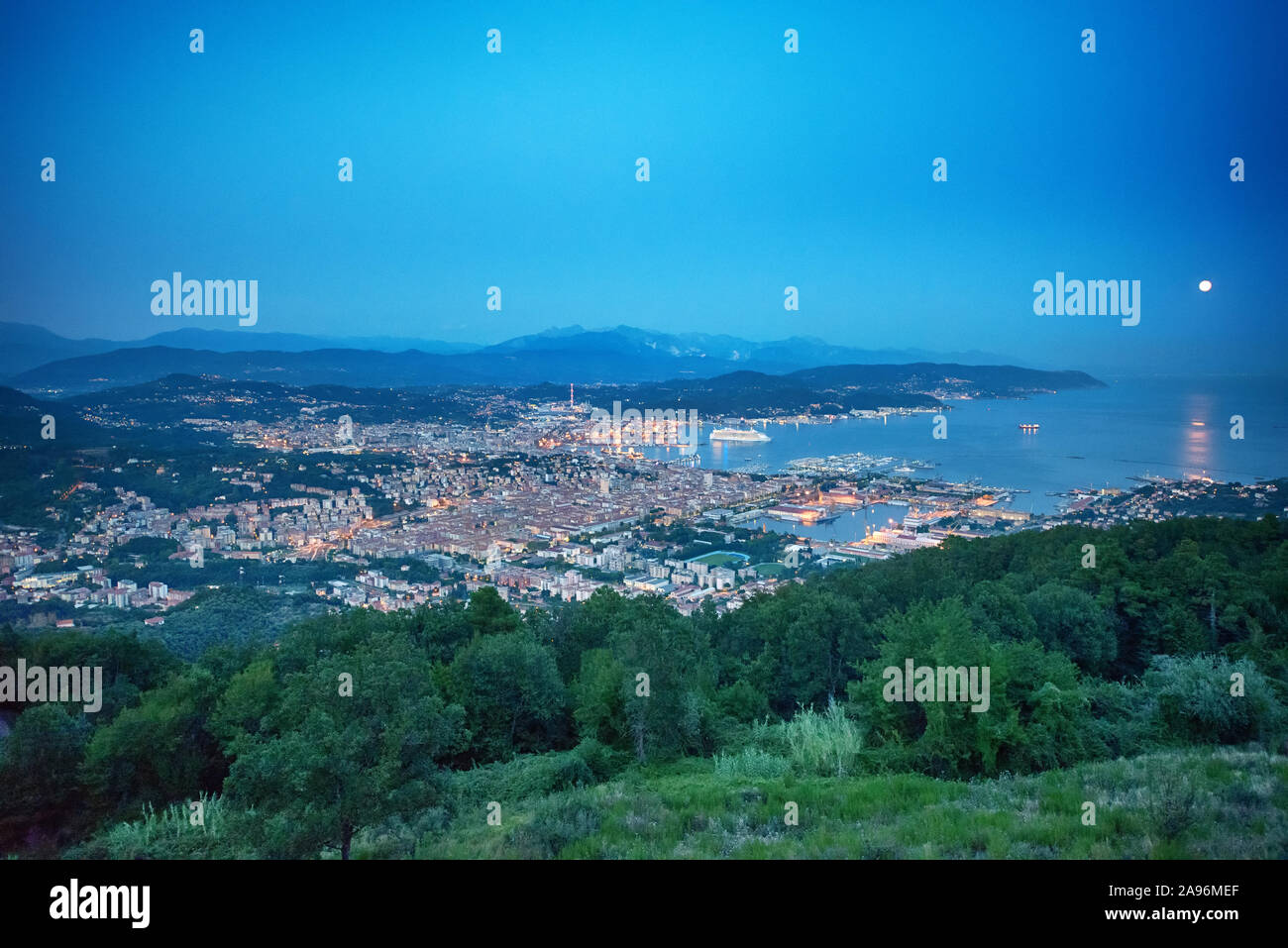 Vista in elevazione al golfo di La Spezia, Italia al tramonto con luci scintillanti diventando visibili nella città di seguito in un paesaggio panoramico Foto Stock