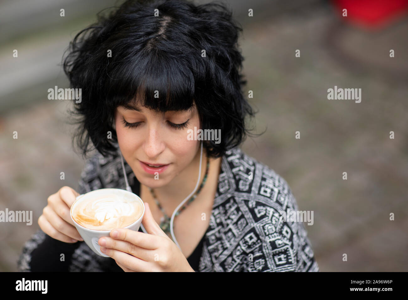 Giovane donna con il computer portatile al di fuori a bere caffè Foto Stock