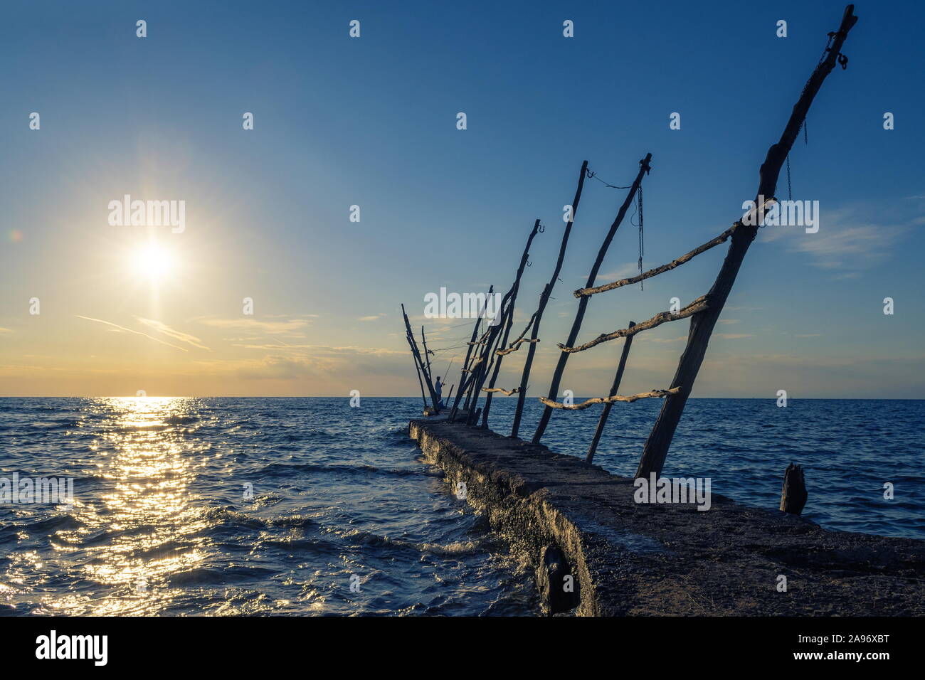 Panorama di un molo vecchio e un pescatore al tramonto sul tempo Croatian Coastal Town Savudrija. Viaggi, turismo e vacanza. Foto Stock