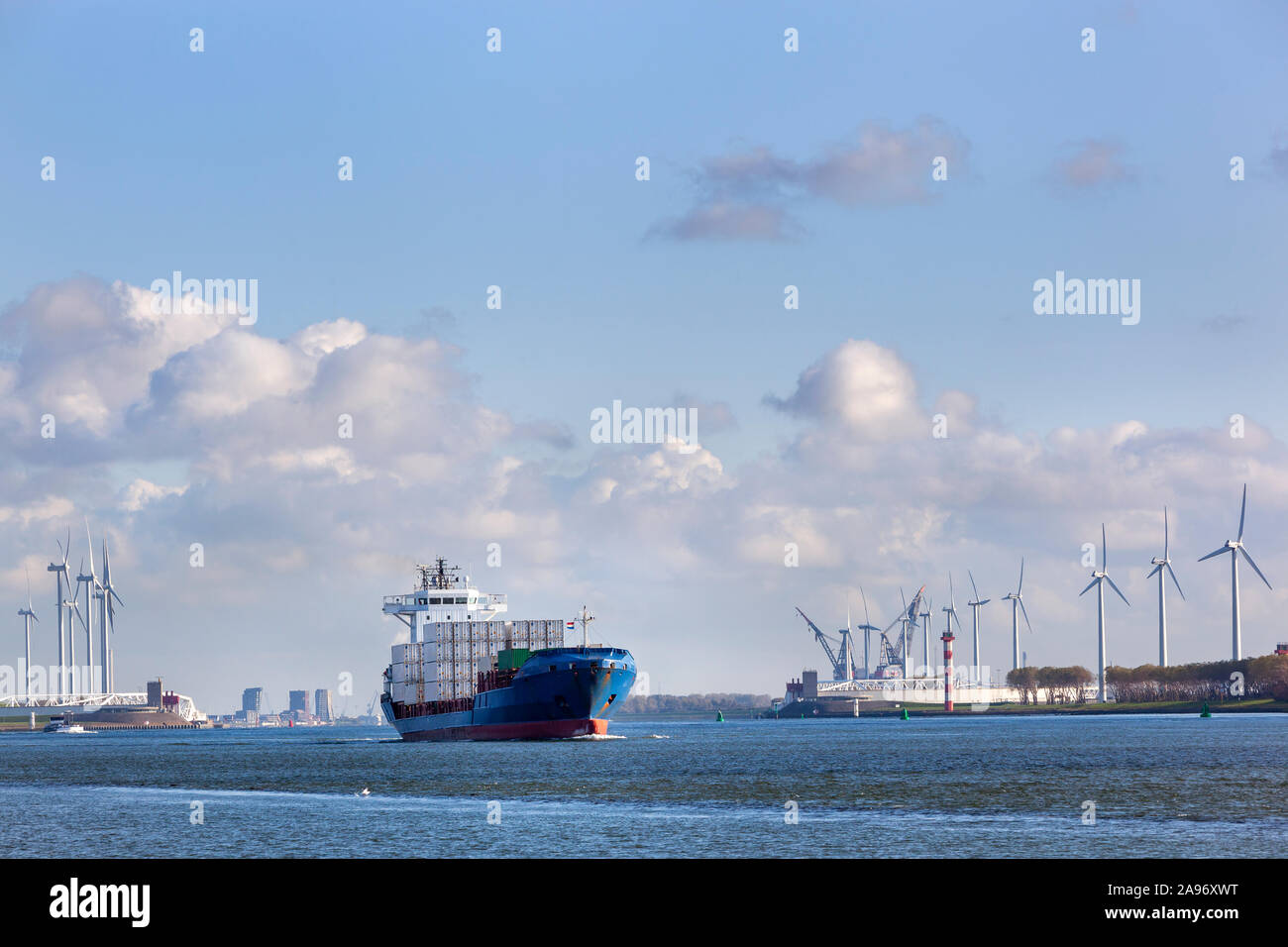 Contenitore nave sul canal Hartelkanaal a Rotterdam nei Paesi Bassi con il Maeslantkering vicino le turbine in background Foto Stock