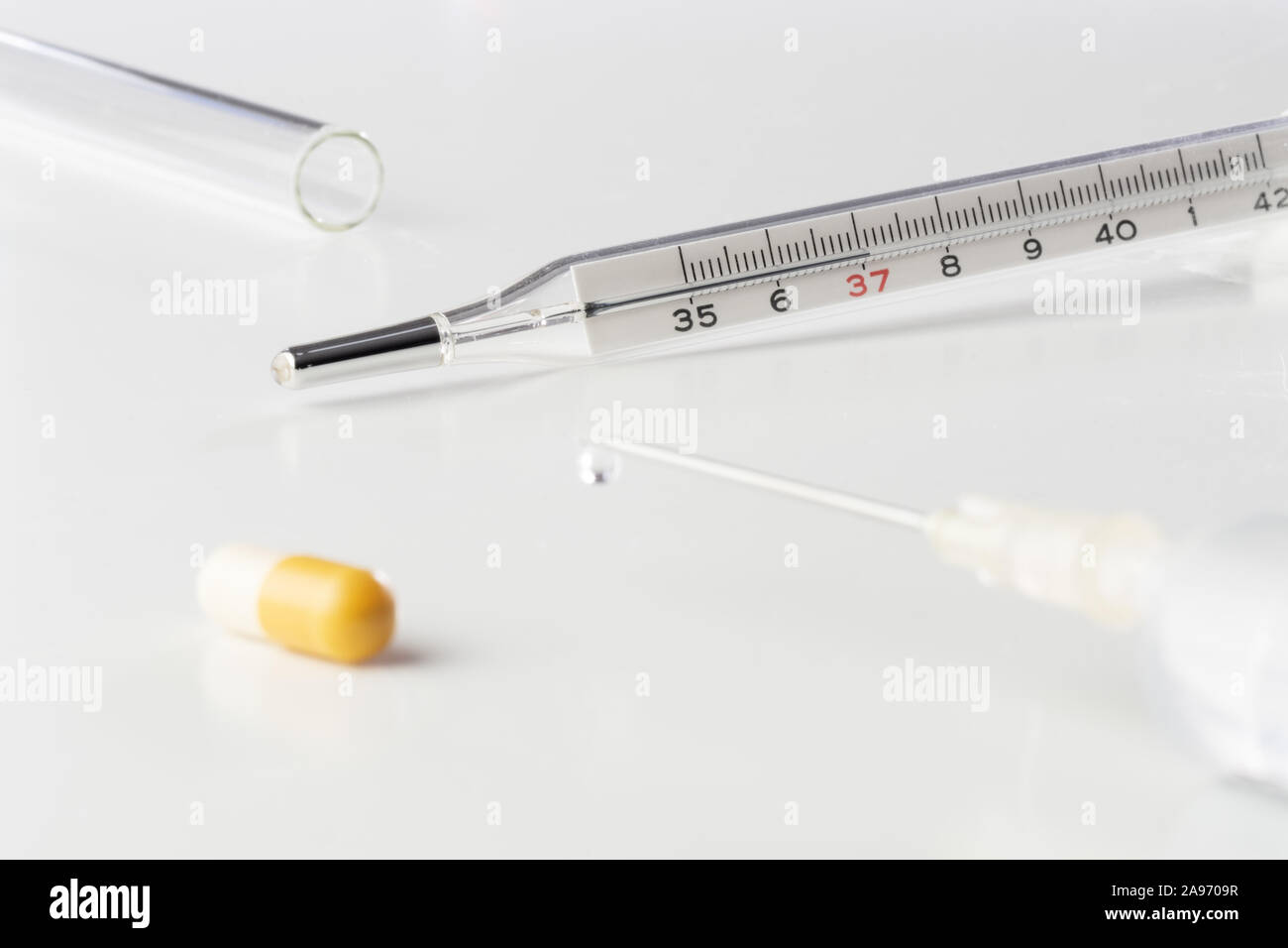 Termometro medico pillola, capsula, vaccino nella siringa medica e tubo di vetro isolato su sfondo bianco. La vaccinazione, influenza, medicina, farmacia, pedia Foto Stock