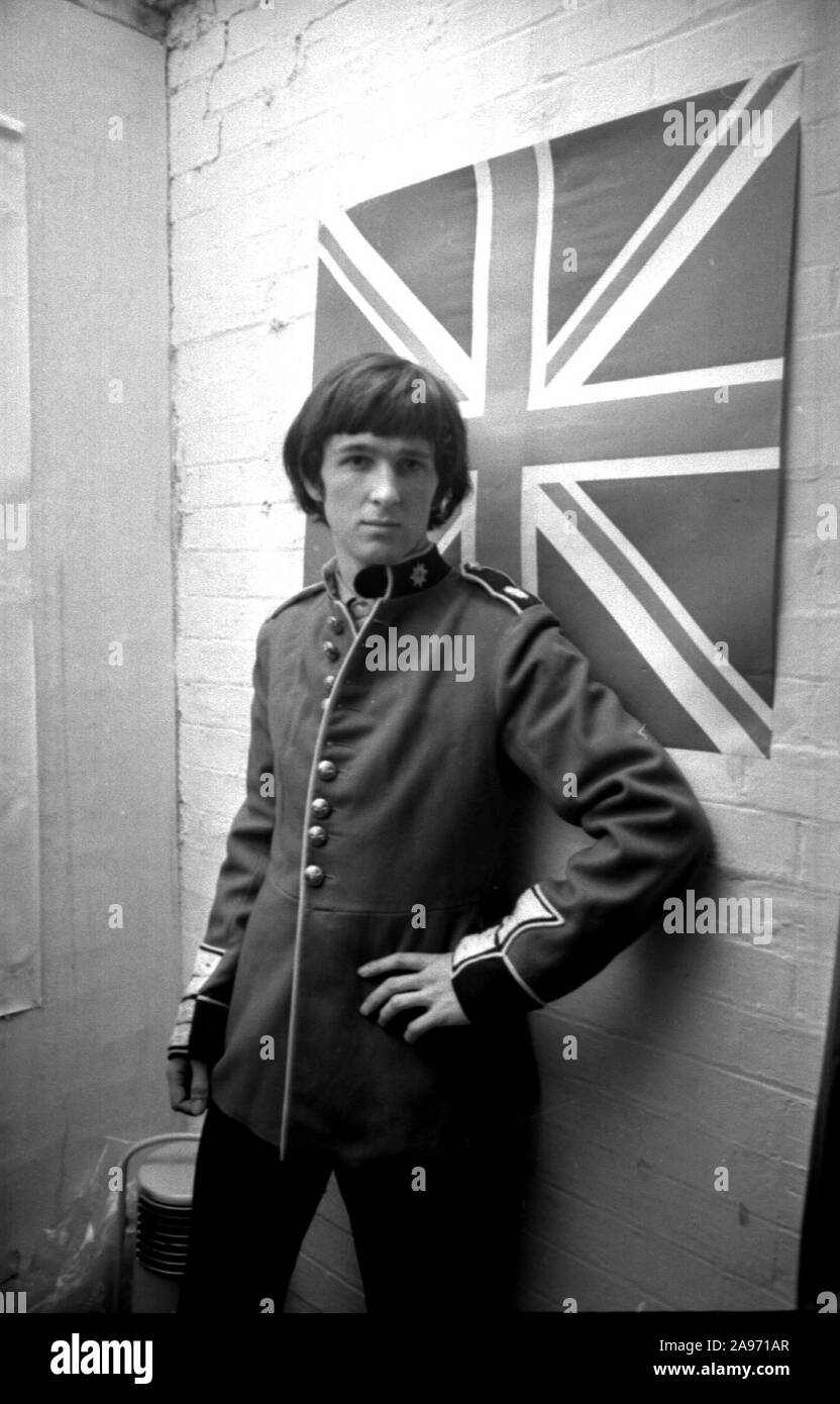 Un giovane uomo prova su una tunica di Grenadier militare in stile scarlatto Kitchener in una boutique in Kings Road, Chelsea durante l'oscillazione 60s di Londra Foto Stock