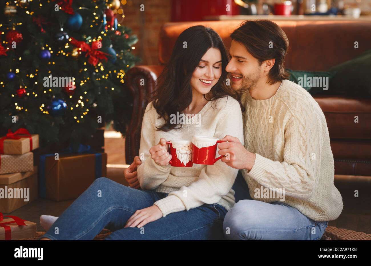 Matura in amore avente xmas cacao accanto a albero di Natale a casa, spazio libero Foto Stock