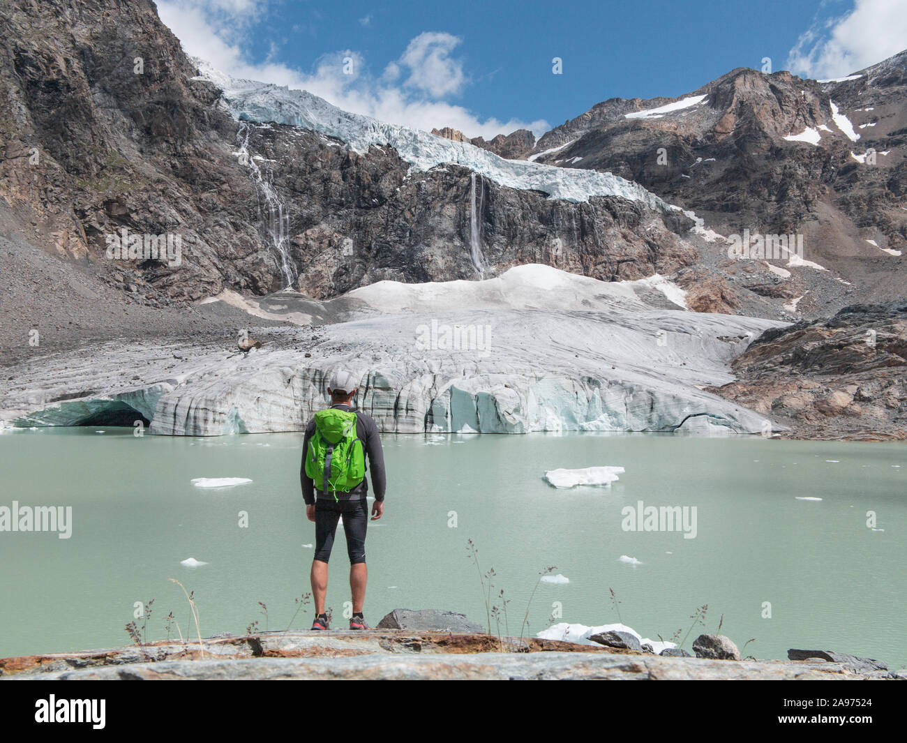 Trekking in montagna, boy guardare un ghiacciaio Glacier e cascata nelle alpi. Foto Stock