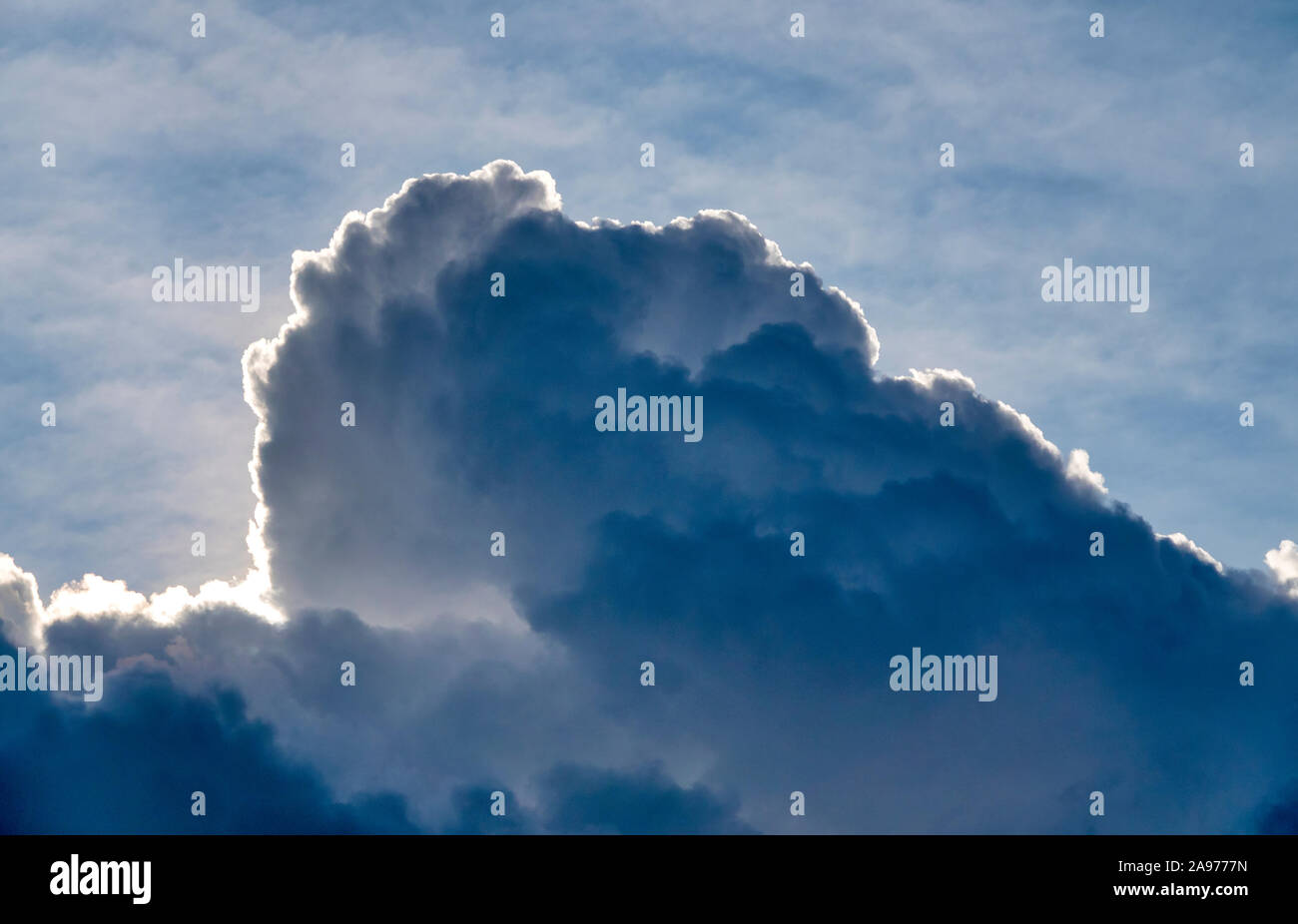 Sun dietro un cumulonimbus calvus cloud Foto Stock