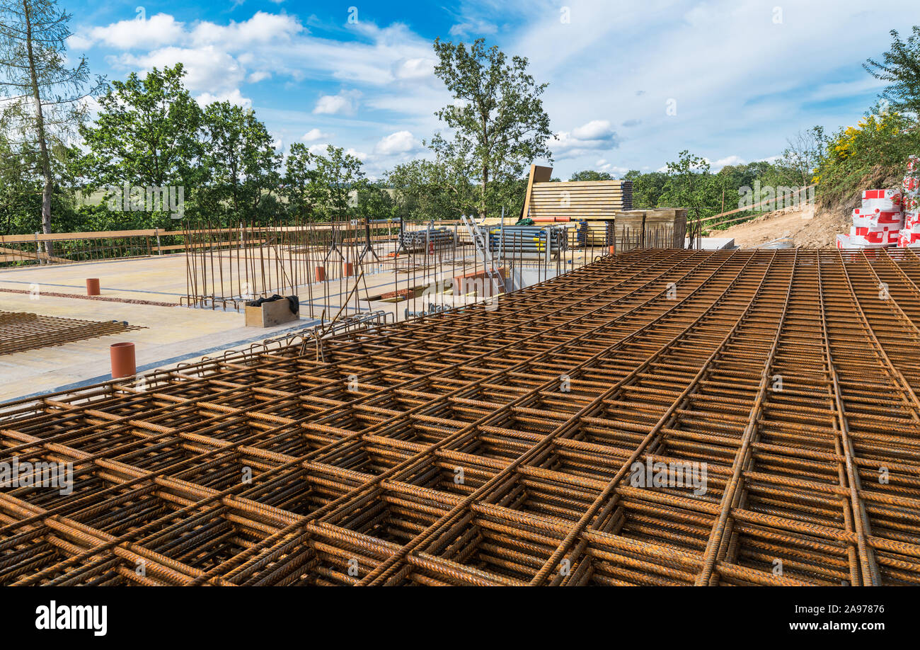 Barre di rinforzo per la griglia di ferroconcrete. Costruzione di fondazioni in alberi verdi. Rebar maglia di colore marrone ruggine i fili di acciaio per cemento armato e muratura. Foto Stock