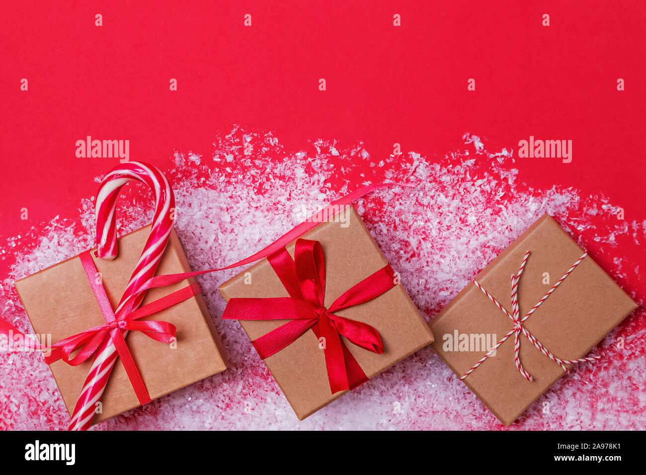 Regali di Natale nelle caselle sulla tabella rossa con la neve. Foto Stock