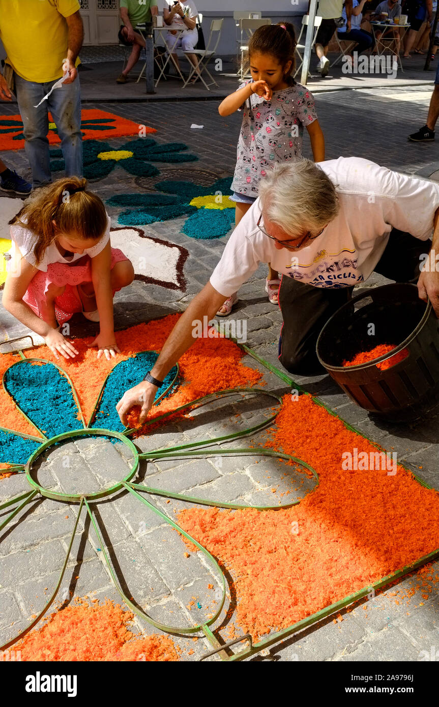 Comunità che fa tappeti colorati di chippings di legno nella strada del villaggio durante Corpus Christi 2019, Carcabuey, Cordoba, Andalusia. Spagna Foto Stock