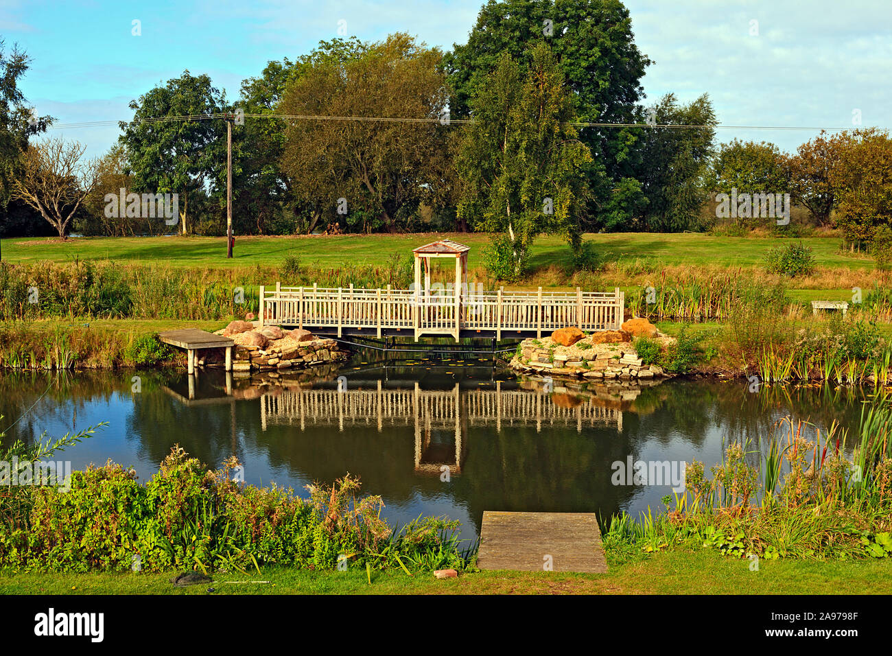 Riflessioni del ponte in legno sul lago per la pesca sportiva Foto Stock