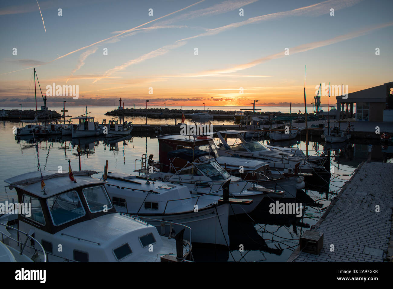 Barche ormeggiate in Cala Bona marina maiorca con una bellissima alba piena di brillanti e colori dorati. Foto Stock