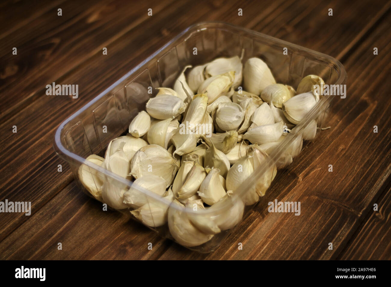 Primo piano della varietà bianca spicchi di aglio ( Allium sativum ), piantine preparate per la semina autunnale, aglio in un vassoio di plastica su sfondo di legno. Foto Stock