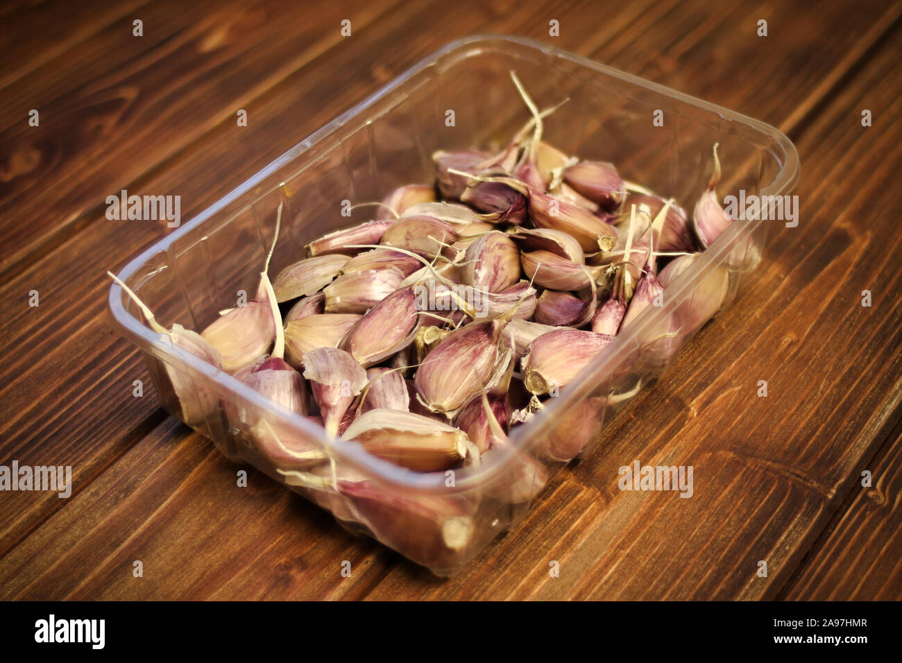 Primo piano della rosa / viola / viola varietà di spicchi di aglio ( Allium sativum), Piantine preparate per la semina autunnale, aglio in un vassoio di plastica su legno Foto Stock
