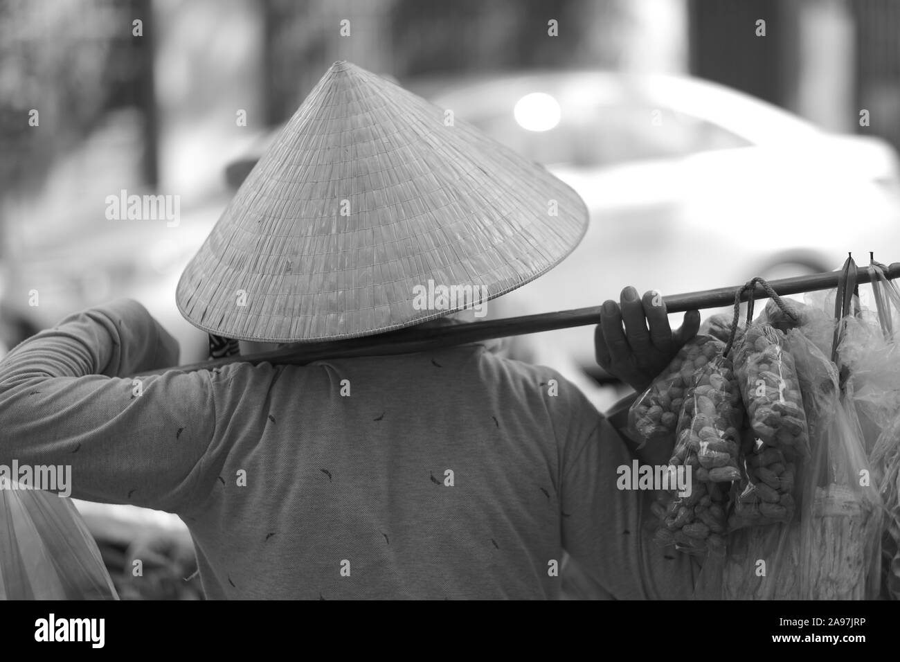 I dadi di un commerciante in un cappello di paglia trasporta merci sulle sue spalle. Il Vietnam Foto Stock