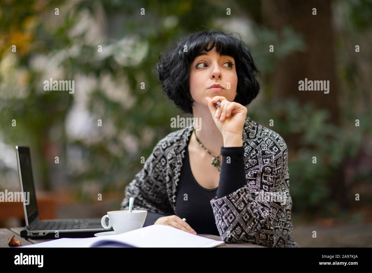 Giovane donna con il computer portatile al di fuori a bere caffè Foto Stock