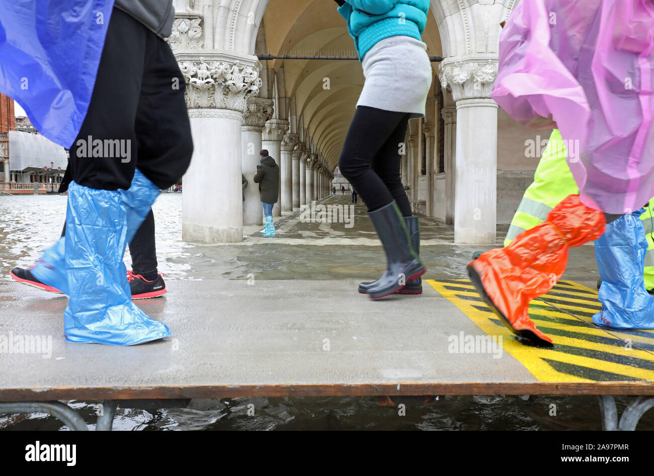 La gente che camminava sul sentiero sopraelevato passerella durante l'imponente alluvione in Venezia in Italia Foto Stock