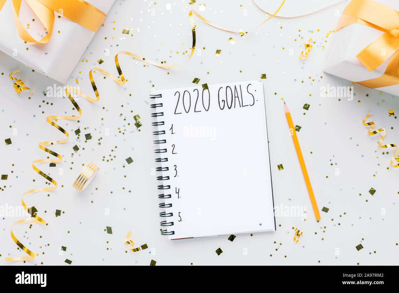 Felice anno nuovo pianificazione. Notebook con 2020 obiettivi e confezioni regalo su sfondo bianco, spazio di copia Foto Stock