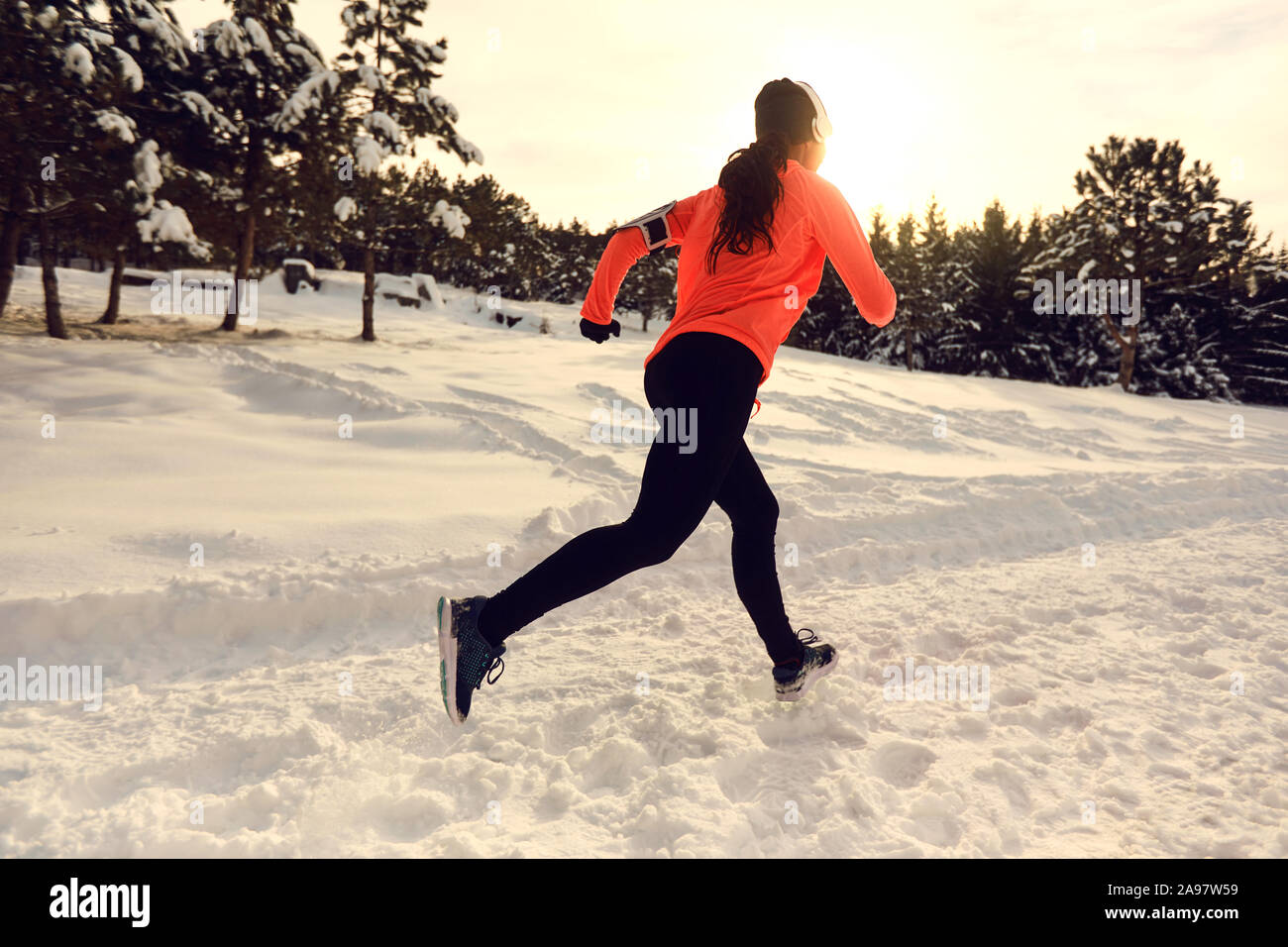 La donna corre nella foresta al tramonto in inverno. Foto Stock