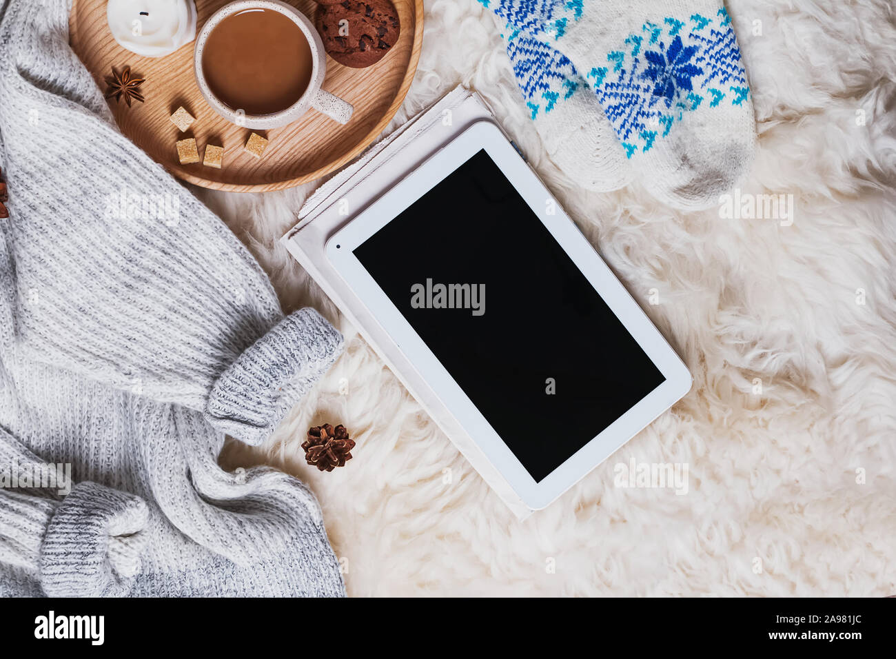 Tablet con schermo vuoto, un maglione pesante e una tazza di caffè sulla pelliccia Foto Stock
