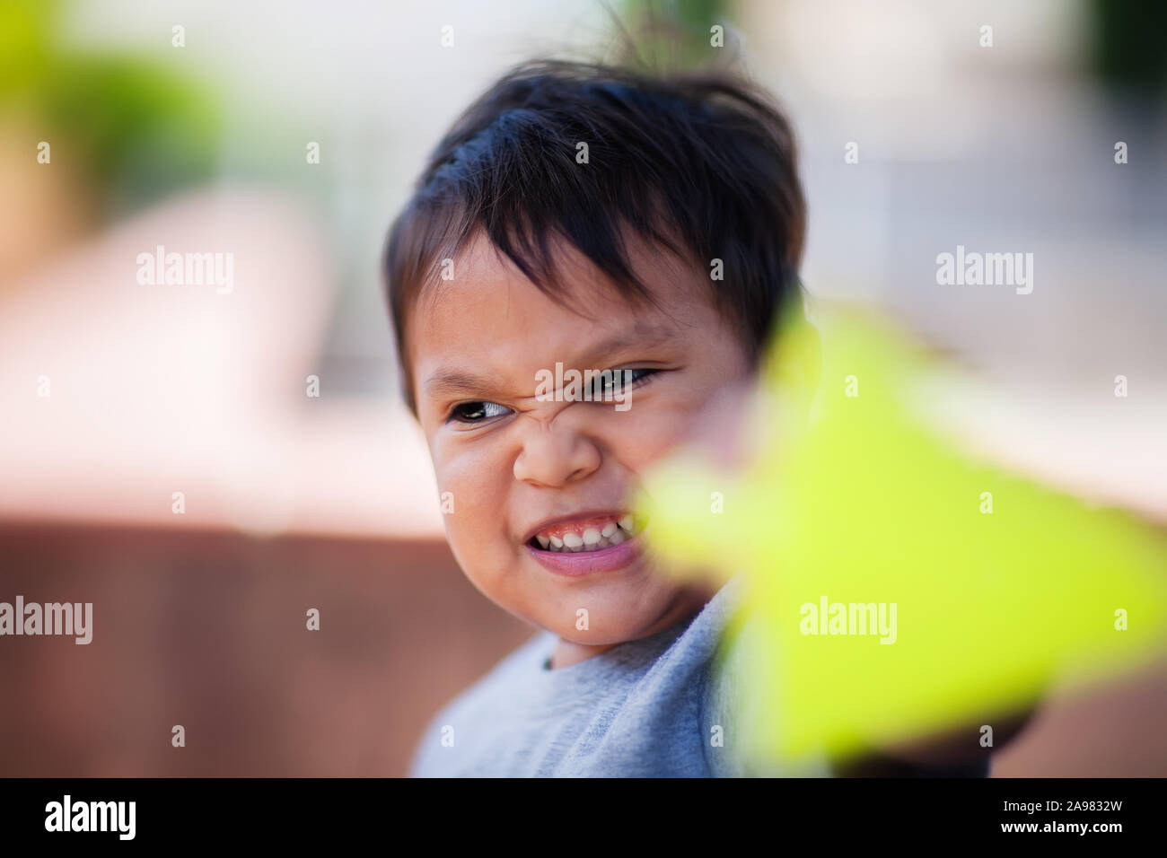 Un grazioso piccolo ragazzo giocando con i suoi giocattoli e usando la sua immaginazione in un ambiente all'aperto. Foto Stock