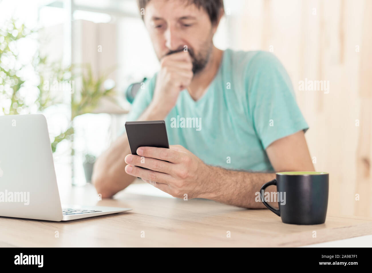 Ricezione di sconvolgere un messaggio di testo sul telefono cellulare, close up maschio utilizza lo smartphone in ambienti interni Foto Stock