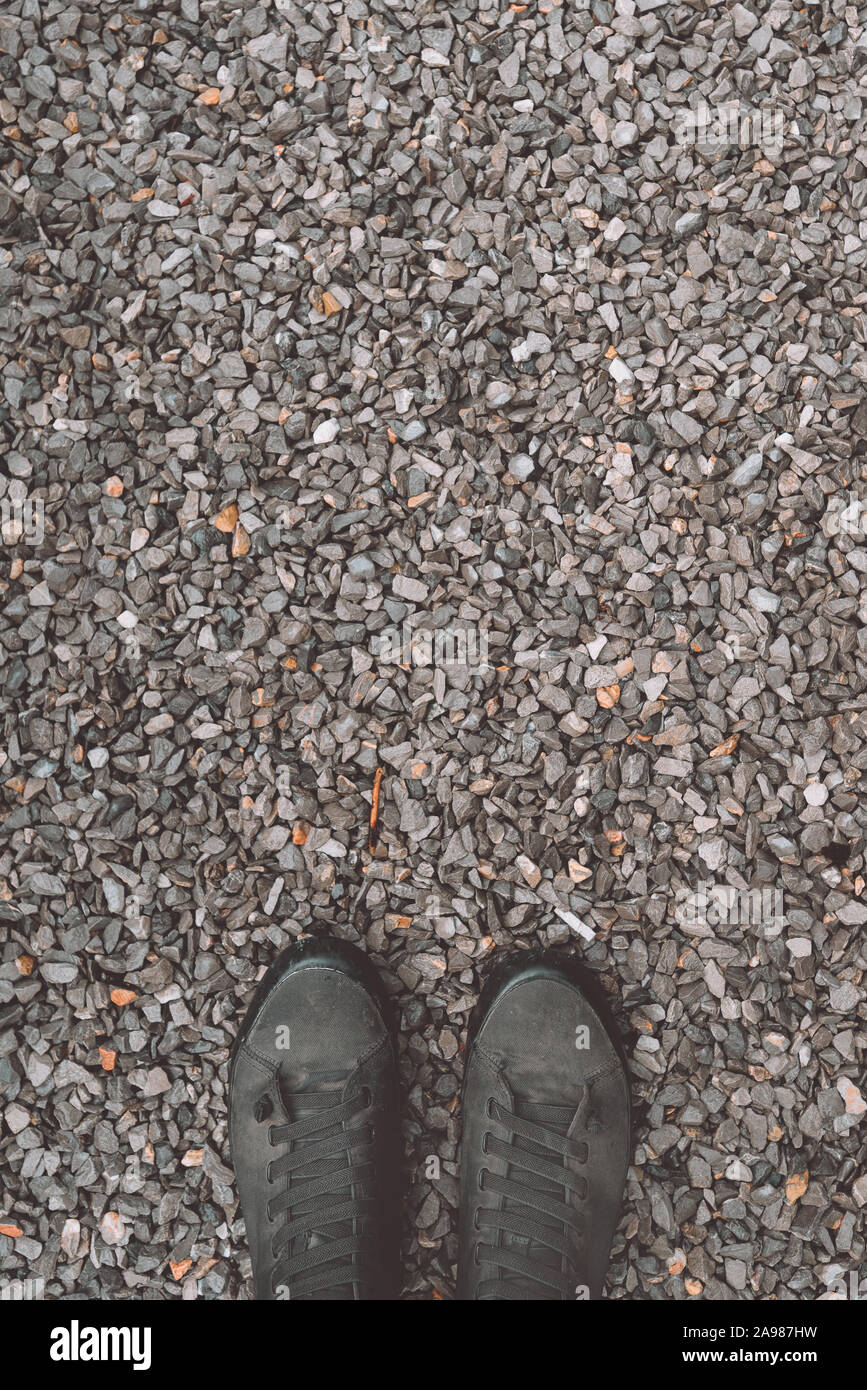 In piedi sulla ghiaia di massa di pietra, indossato scarpe da ginnastica da sopra con lo spazio di copia Foto Stock