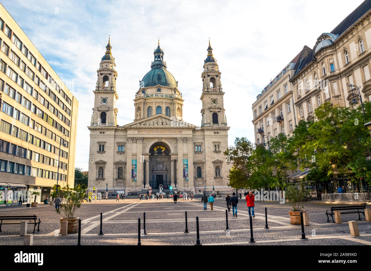 Budapest, Ungheria - Novembre 6, 2019: la Basilica di Santo Stefano e adiacente piazza con la gente. Cattolica romana basilica, un esempio di architettura neoclassica. Brutto edificio socialista proprio accanto ad esso. Foto Stock