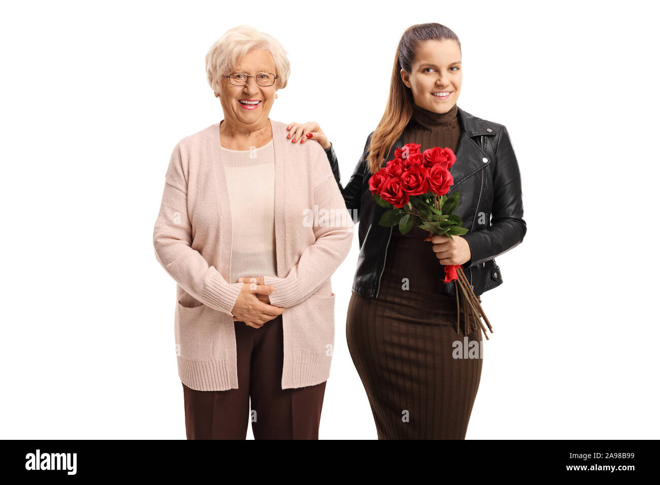 La nipote tenendo un mazzo di rose e in piedi accanto alla sua nonna isolata su sfondo bianco Foto Stock