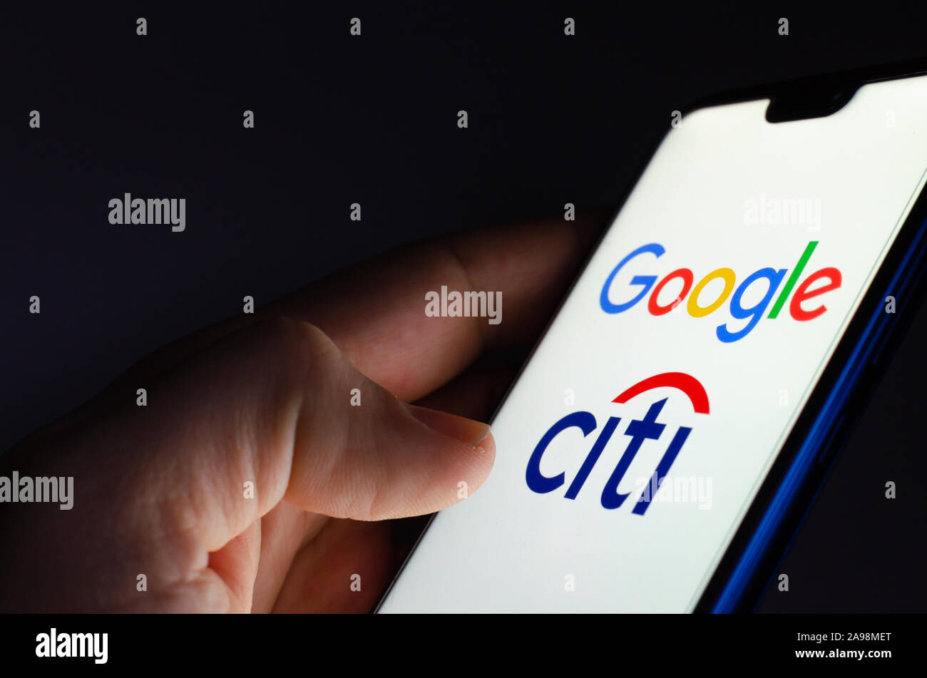 Google e Citigroup logo su schermo incandescente in mani. Foto illustrative per la notizia che Google ha collaborato con la Citibank nel progetto denominato Cache Foto Stock