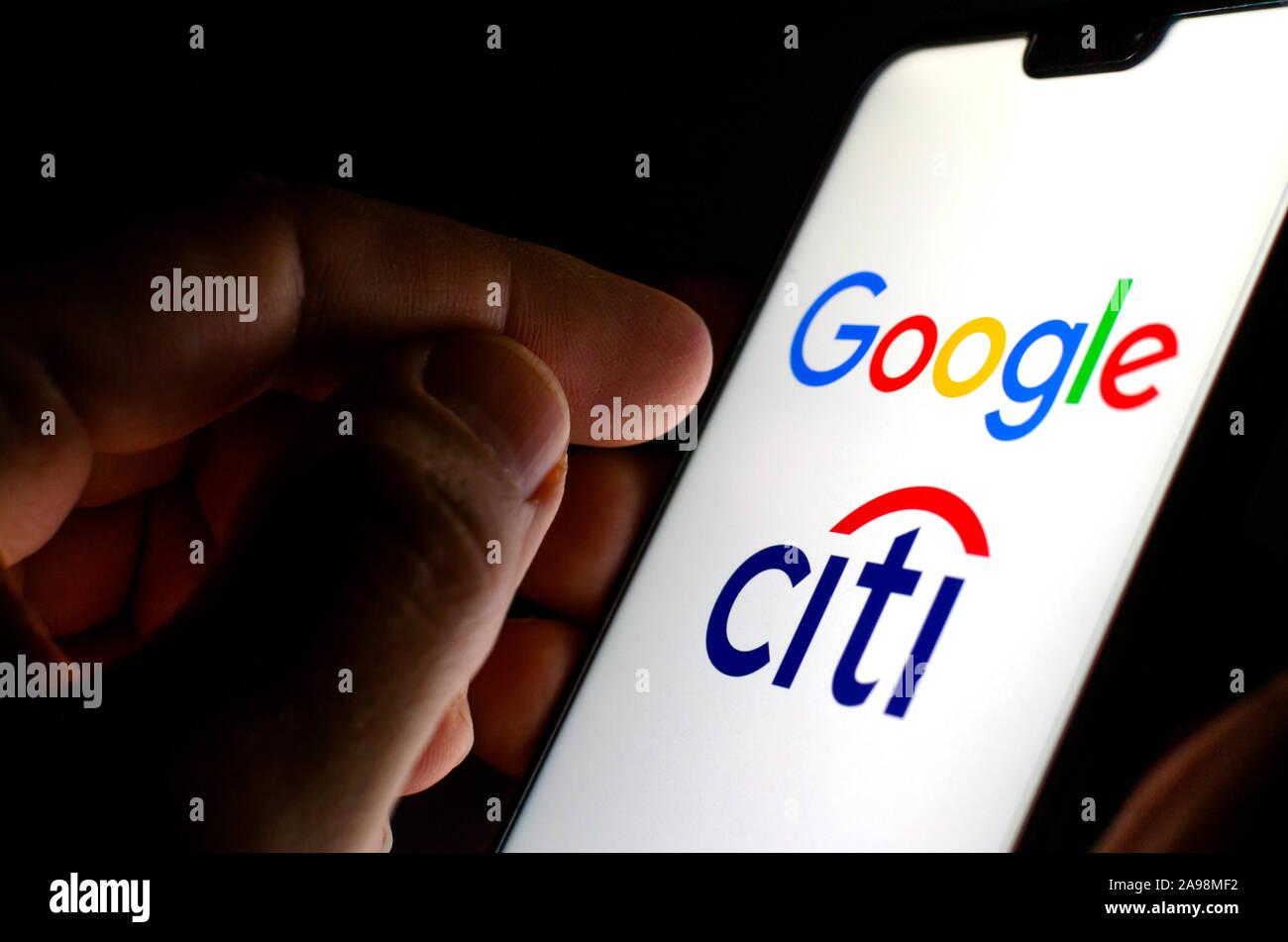 Google e Citigroup logo su schermo incandescente in mani. Foto illustrative per la notizia che Google ha collaborato con la Citibank nel progetto denominato Cache Foto Stock