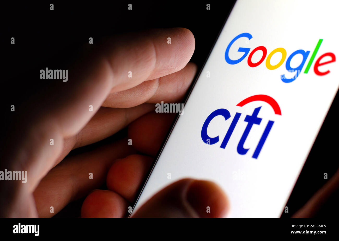 Google e Citigroup logo su schermo incandescente in mani. Foto illustrative per la notizia che Google ha collaborato con la Citibank nel progetto denominato Cache Foto Stock