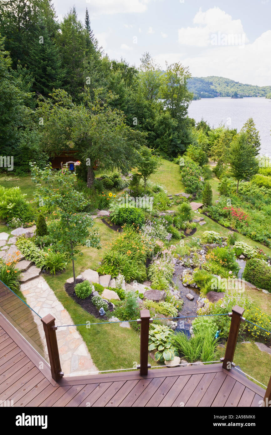 Vista dall'alto di elementi di rinforzo inclinati residenziale giardino cortile con rock refilato stream delimitato da orange Hemerocallis - Daylily, rosa Astilbe fiori Foto Stock